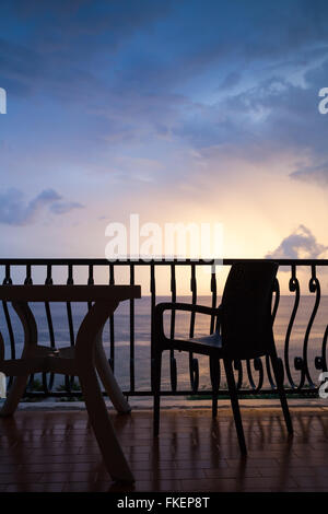 Sessel und Tisch stehen auf dem Balkon. Meerblick über helle Sonnenaufgang Himmel Stockfoto