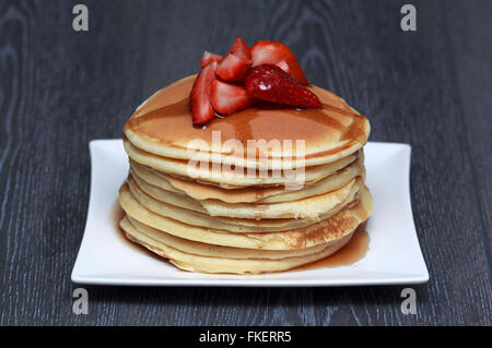 Stapel von Pfannkuchen mit Erdbeeren auf dunklem Holz Stockfoto