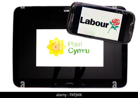 Ein Tablet mit dem Plaid Cymru-Logo drauf und ein Smartphone mit dem Labour-Logo drauf vor einem weißen Hintergrund. Stockfoto