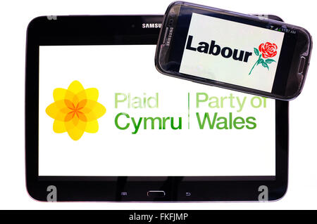 Ein Tablet mit dem Plaid Cymru-Logo drauf und ein Smartphone mit dem Labour-Logo drauf vor einem weißen Hintergrund. Stockfoto