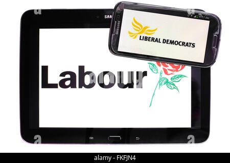 Ein Tablet mit der Labour-Partei-Logo drauf mit einem Smartphone mit den Liberaldemokraten Logo drauf vor einem weißen Hintergrund. Stockfoto