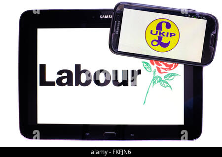 Ein Tablet mit der Labour-Partei-Logo drauf mit einem Smartphone mit der UKIP-Logo drauf vor einem weißen Hintergrund. Stockfoto