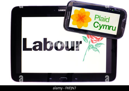 Ein Tablet mit der Labour-Partei-Logo drauf mit einem Smartphone mit dem Plaid Cymru Logo auf einem weißen Hintergrund. Stockfoto