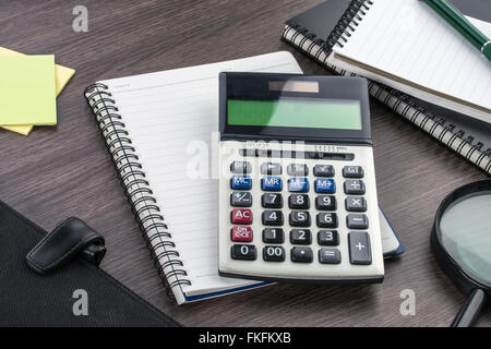 Notizbuch, Stift, Kleber Hinweis und Lupe mit Rechner auf dem Schreibtisch Stockfoto