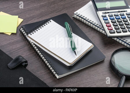 Notizbuch, Stift, Kleber Hinweis und Lupe mit Rechner auf dem Schreibtisch Stockfoto