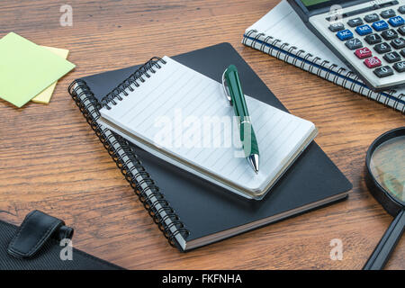 Notizbuch, Stift, Kleber Hinweis und Lupe mit Rechner auf dem Schreibtisch Stockfoto