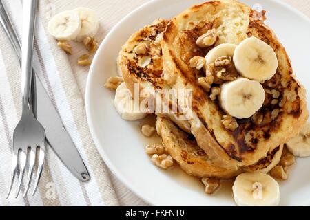 Teller mit leckeren French Toast mit Bananen, Walnüssen und tropfende Ahornsirup, Draufsicht Stockfoto
