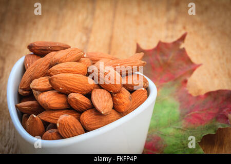 Gesundes Essen, gut für die Gesundheit des Herzens.  Mandeln in der Schüssel auf herbstliche Hintergrund weiß Stockfoto