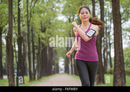 Junge Asiatin Joggen im Wald, Handy-lifestyle Stockfoto