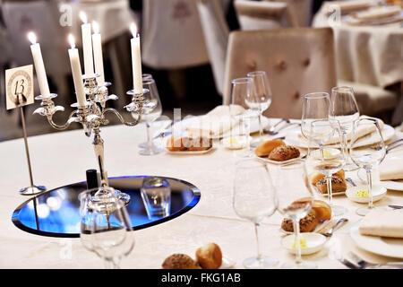 Brennenden Kerzen in einem Kronleuchter auf eleganten Esstisch Stockfoto