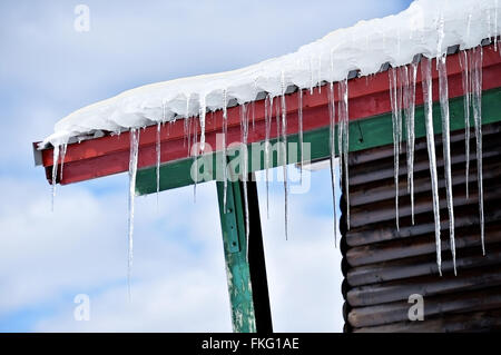 Winter-Detail mit Schmelzender Eiszapfen auf dem Dach des Chalet aus Holz Stockfoto