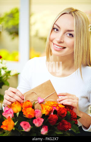 Junge Frau mit Liebesbotschaft ins Blumenstrauß Stockfoto