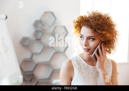 Nachdenkliche schöne junge Geschäftsfrau reden über Handy im Büro Stockfoto