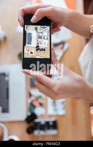 Nahaufnahme der Hände der jungen Frau am Fotografieren von Objekten an ihrem Arbeitsplatz mit smartphone Stockfoto