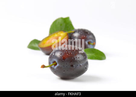 Nahaufnahme von zweieinhalb gewaschenen Pflaumen auf weißem Hintergrund Stockfoto