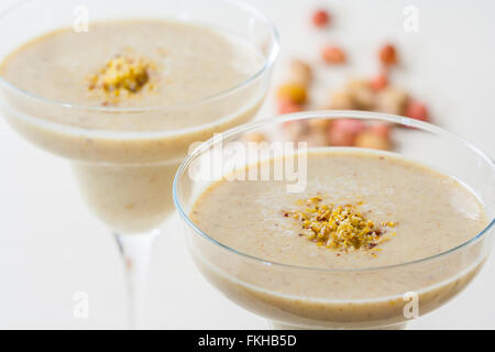 Frische Smoothies mit Banane und gekrönt mit gemahlenen Pistazien Nüssen. Stockfoto