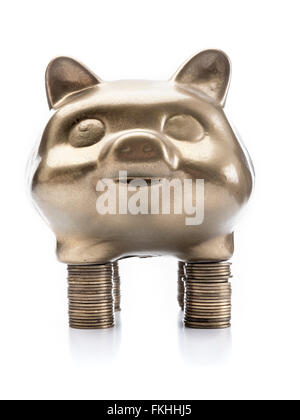 Goldene Sparschwein stehend auf Haufen von Münzen auf weißem Hintergrund Stockfoto