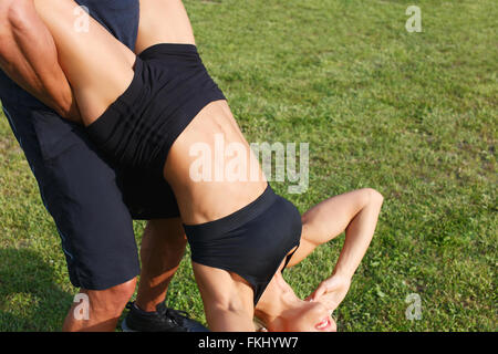 Junge Frau dabei Sit Ups mit Personaltrainer in Natur, extreme Training, im freien Stockfoto
