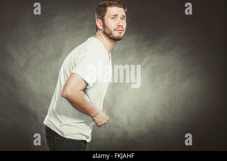Mann leidet unter Magen Schmerzen Schmerzen im Unterleib. Junger Mann im Studio auf schwarz. Stockfoto