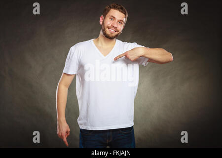 Porträt von glücklich modische casual Mann weiße leere Shirt mit leeren textfreiraum auf sich selbst gerichtet. Junger Kerl. Stockfoto