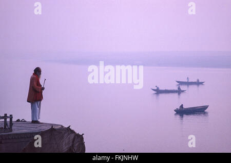 Indische, Hindu, heilig, Mann, Sadhu, betet, betet, das Gebet, das in Richtung der Morgen, Sonnenaufgang von ghats über dem Fluss Ganges, Varanasi, Benares, Uttar Pradesh, Indien Stockfoto