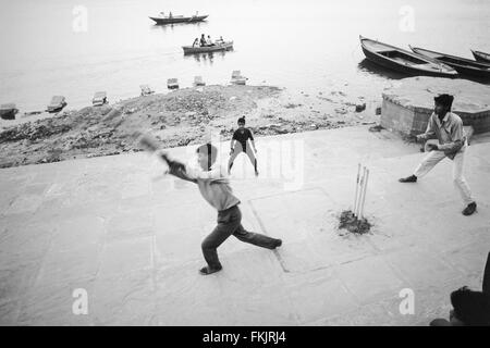 Lokalen Jungen, auf dem baden Ghat, Spielen, beliebt, nationalen, Sport, der, Kricket, bei Sonnenaufgang. Eine gute schlagen und die Kugel geht in den Fluss Stockfoto