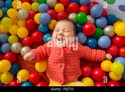 Babymädchen lachend in eine sensorische Bällebad Stockfoto