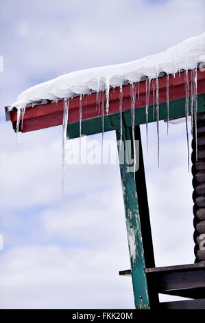 Winter-Detail mit Schmelzender Eiszapfen auf dem Dach des Chalet aus Holz Stockfoto