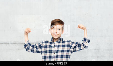 fröhlicher Junge im karierten Hemd zeigt starke Fäuste Stockfoto