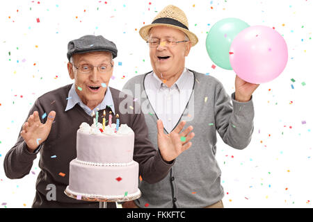 Zwei aufgeregt senior Herren bläst Kerzen auf einem Geburtstag Kuchen isoliert auf weißem Hintergrund Stockfoto