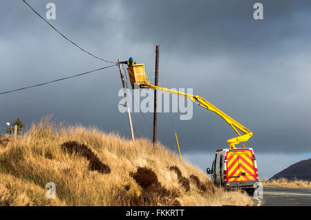 Ein Mann arbeitet auf Kabel Telefonmast im ländlichen Irland in der Nähe von Glenties, County Donegal Stockfoto