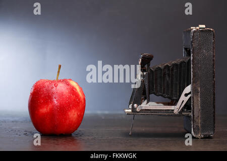 Alten Film-Kamera gegen roter Apfel auf dunklem Hintergrund Stockfoto