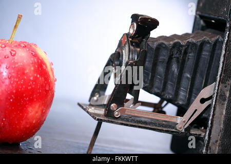 Alten Film-Kamera gegen roter Apfel auf dunklem Hintergrund Stockfoto