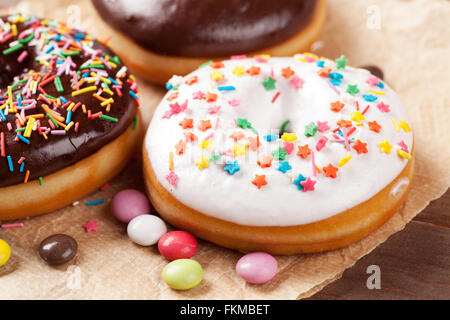 Donuts und Süßigkeiten auf Holztisch Stockfoto