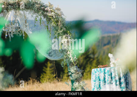 Hochzeit in den Bergen. Schöne Hochzeit Bogen, dekoriert mit Blumen auf dem Hintergrund der Karpaten. Stockfoto