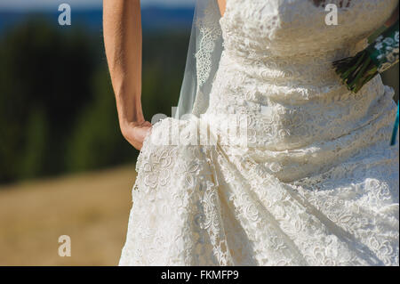 Braut hält ihren Rock Brautkleider in rechten Hand, während sie zu Fuß. Hochzeit in den Bergen. Stockfoto