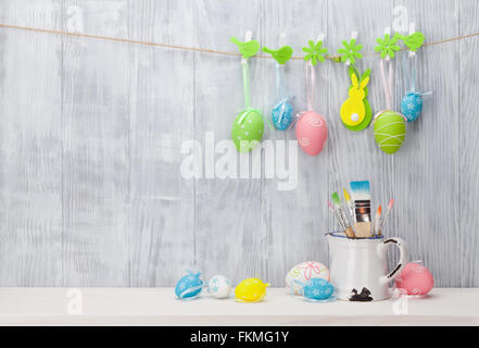 Bunte Ostereier und Bürsten auf Regal vor Holzwand. Zeigen mit textfreiraum an Stockfoto