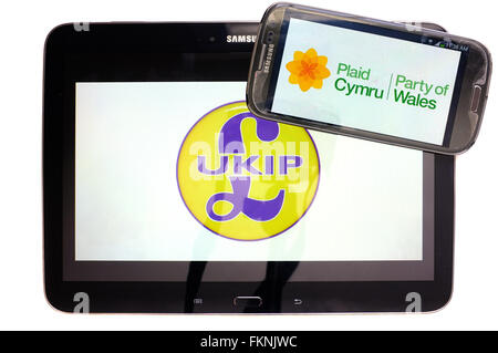 Die UKIP und Plaid Cymru-Logos auf den Bildschirmen der ein Tablet und Smartphone vor einem weißen Hintergrund angezeigt. Stockfoto