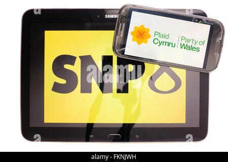 Die SNP und Plaid Cymru-Logos auf den Bildschirmen der ein Tablet und Smartphone vor einem weißen Hintergrund angezeigt. Stockfoto