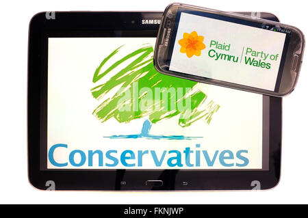 Die Konservativen und Plaid Cymru Logos auf den Bildschirmen der ein Tablet und Smartphone vor einem weißen Hintergrund angezeigt. Stockfoto