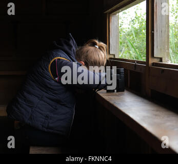 Verschlafene junge Frau in einem Versteck Vogelbeobachtung mit ihrem Fernglas nach einem sehr langen Tag. Juni 2015 Stockfoto