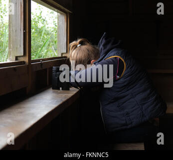 Verschlafene junge Frau in einem Versteck Vogelbeobachtung mit ihrem Fernglas nach einem sehr langen Tag. Juni 2015 Stockfoto