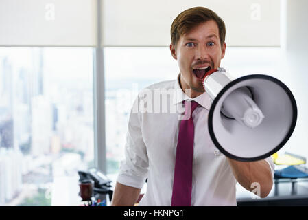 Junge Geschäftsstelle Arbeiter halten Megaphon und mit Vertrauen und lustige Ausdruck in die Kamera zu sprechen. Textfreiraum Stockfoto