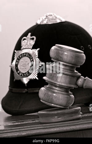 Rechtsbegriff Metropolitan Police Helm mit Richterhammer in London Recht Gerichte Situation UK (B&W getönten) Stockfoto