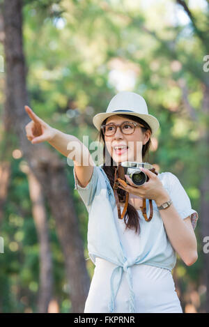 Schöne junge Mädchen fröhlich mit Retro-Kamera fotografieren, zeigt im freien Stockfoto