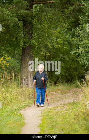 Eine ältere Frau beschäftigt sich mit Nordic walking in der Natur. Stockfoto