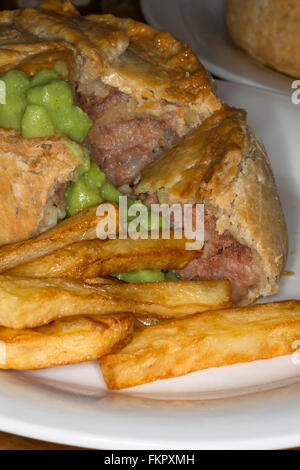 Ein traditionelles englisches, vor allem im Norden, Schüssel mit Corned Beef und Kartoffelkuchen serviert mit Erbsenpüree und Chips/Pommes Frites. Stockfoto