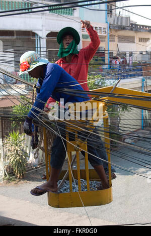 Zwei Männer arbeiten an Strom- und Telefonleitungen Linien in Kampong Cham, Kambodscha. Stockfoto