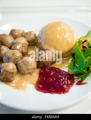 Eine Platte von IKEA Frikadellen, Kartoffelpüree, Sahne Soße, grüner Salat und Preiselbeer-Sauce. Stockfoto