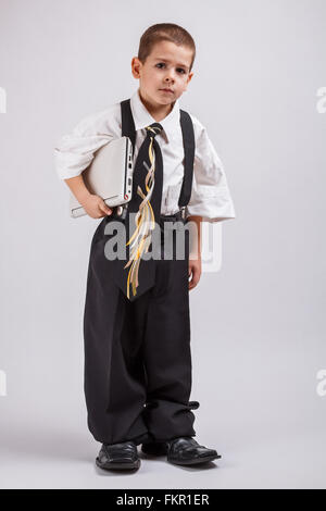 Kleiner Junge gekleidet in übergroßen Anzug Kleidung mit laptop Stockfoto